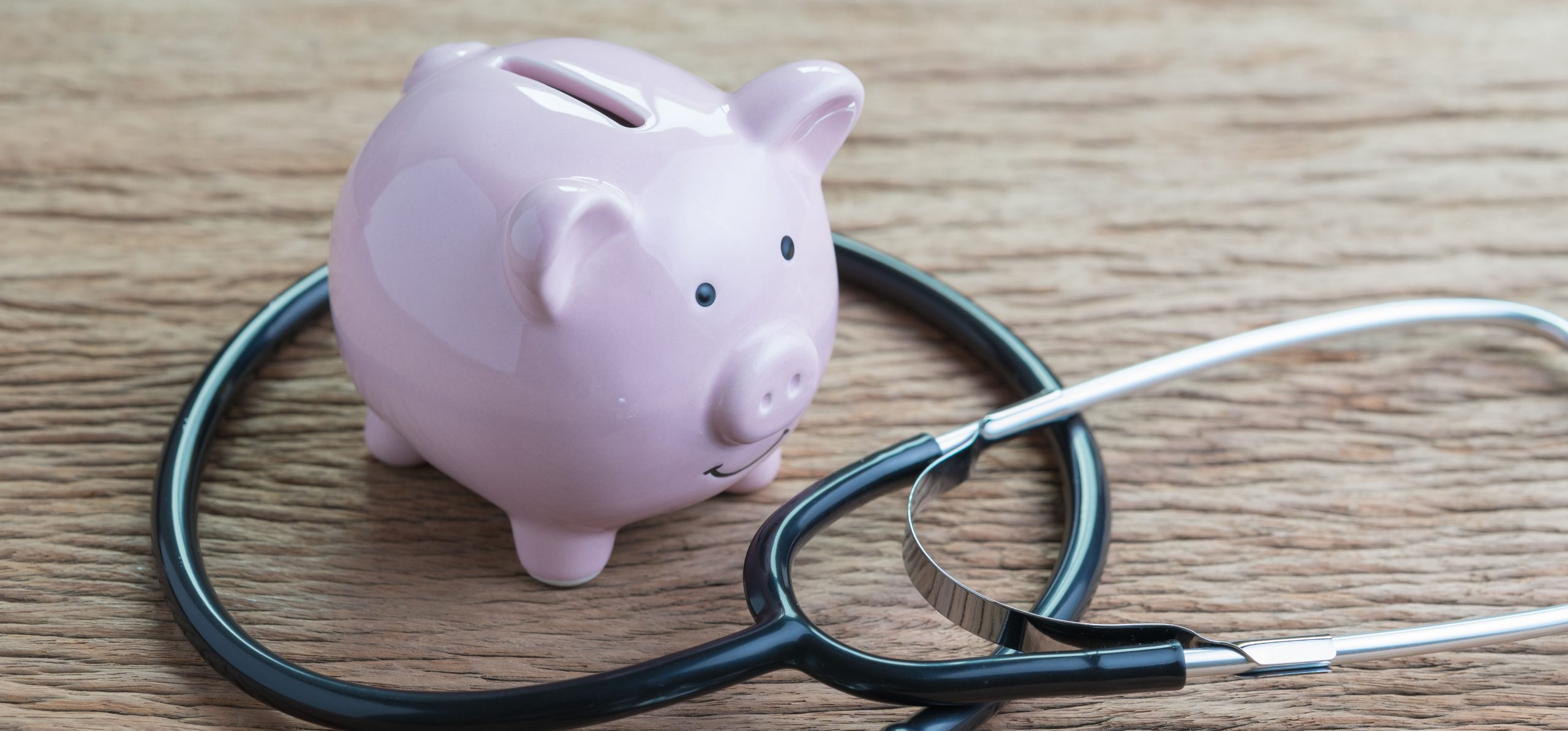 Healthcare, medical, insurance fees or financial health check concept, stethoscope with pink piggy bank on wooden table.