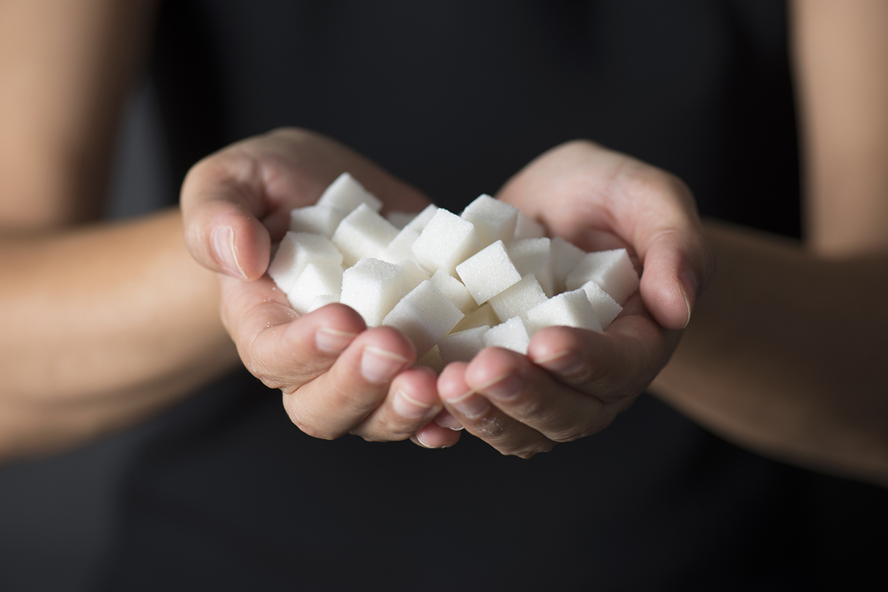 Caucasian female is holding sugar cubes in hand.