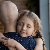 Love can make wonders. Caring small daughter hugging tight holding in arms ill hairless mother fighting with oncology supporting comforting believing in happy future life after good result of therapy