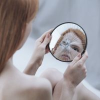 Distorted reflection of a woman in a small, broken mirror