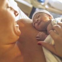 Mother with newborn baby son lying in bed